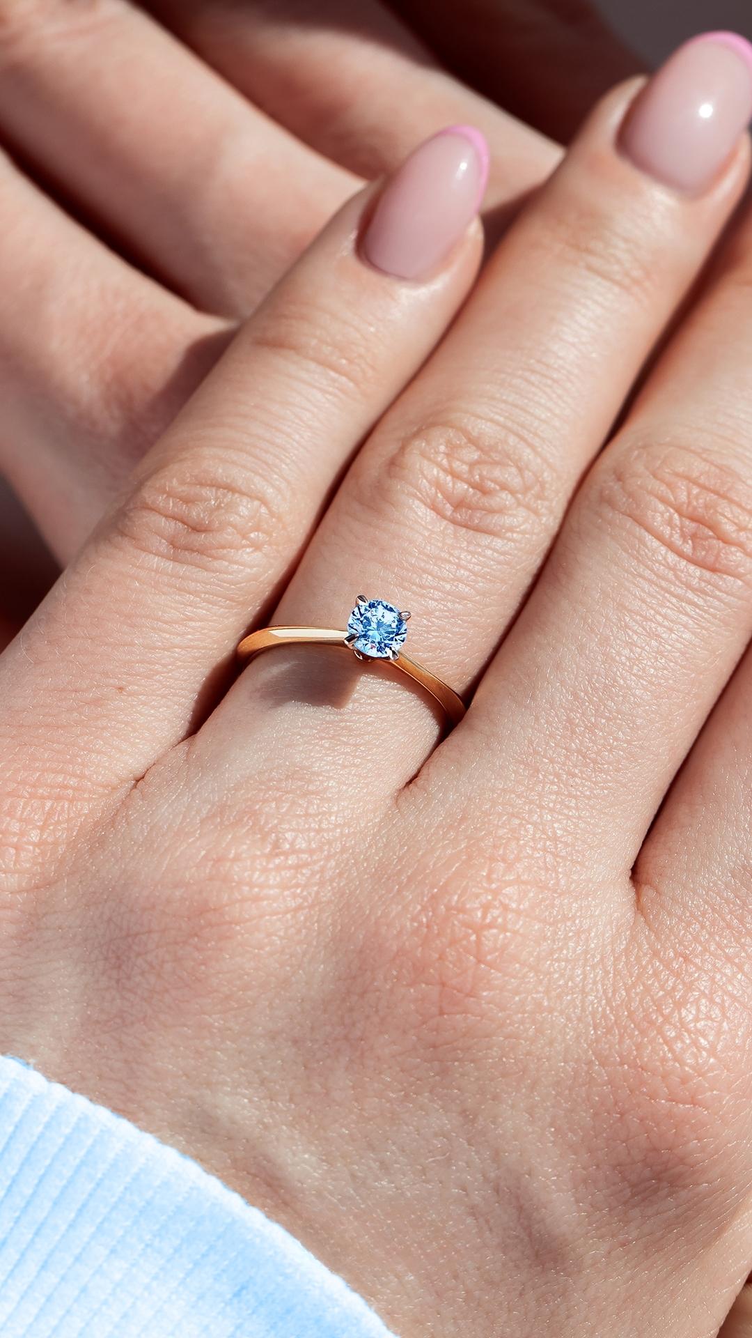 Pierscionek zareczynowy z diament laboratoryjny niebieski 050 ct z zolte zloto angel na palcu